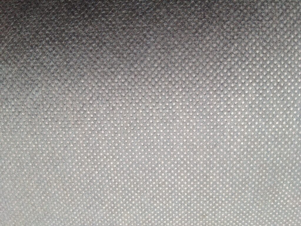 A close-up, macro view showing the random fiber structure of a white nonwoven fabric