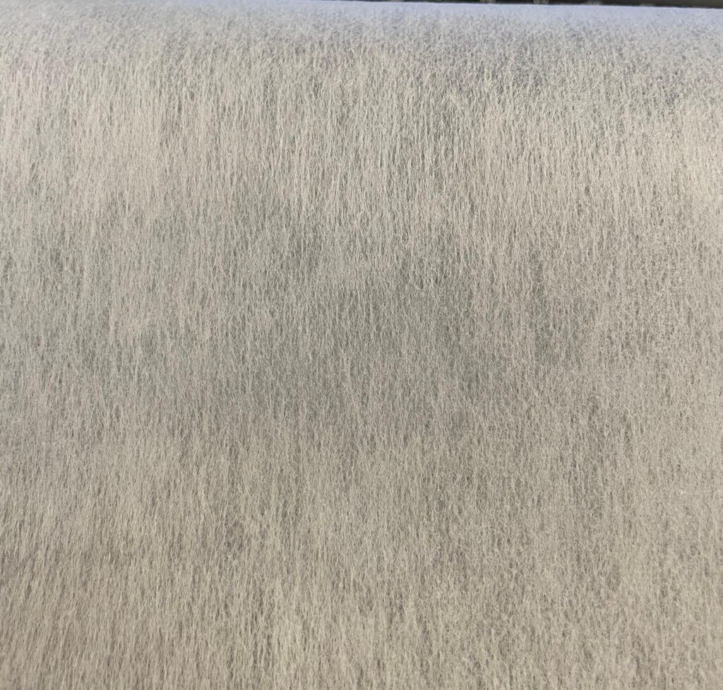A magnified view showing the smooth, uniform surface of a thermally-bonded non-woven fabric