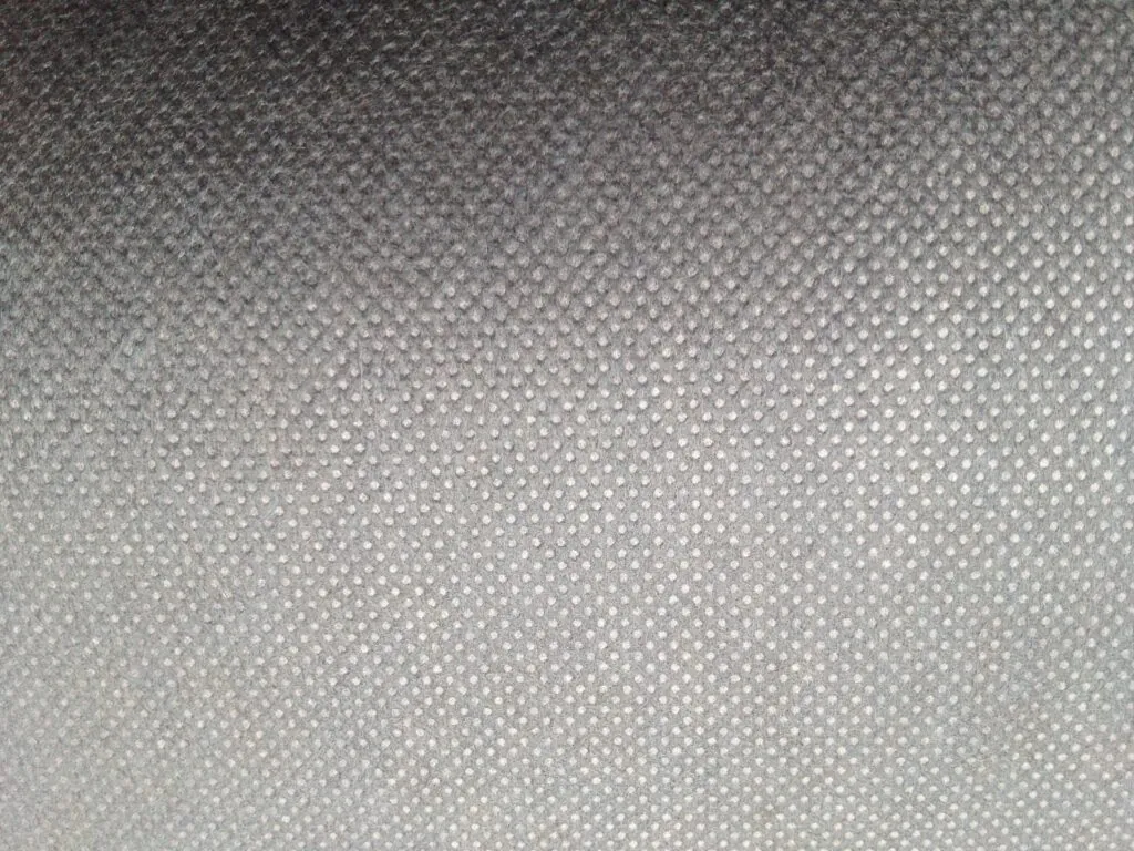 A close-up, macro view showing the random fiber structure of a white nonwoven fabric