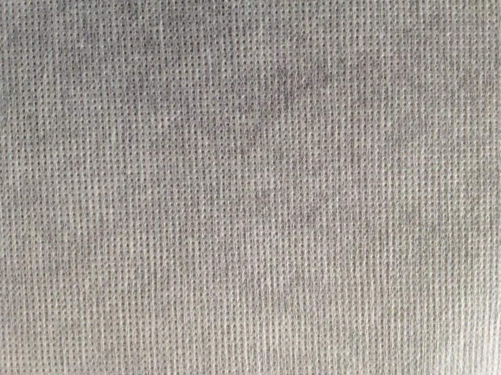 A close-up of a smooth, white thermal bonded polyester fabric